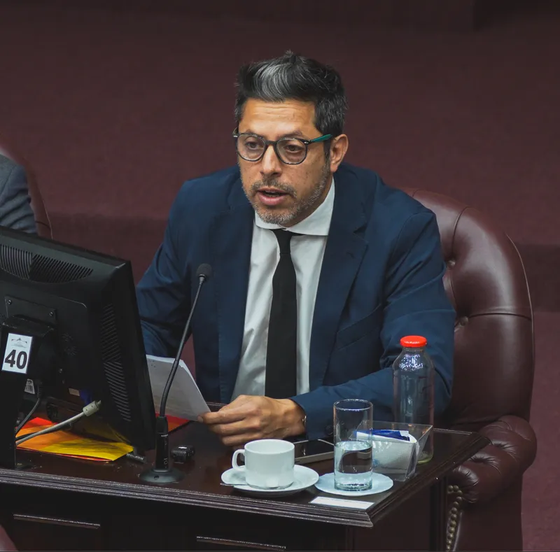 Nicolás González Ferro con anteojos, hablando frente al micrófono desde su banca